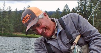 A man smiles while holding a fly fishing rod.