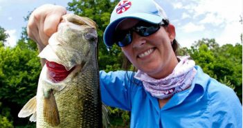 A woman holding up a large bass.