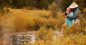 A man and a child fishing in a river.