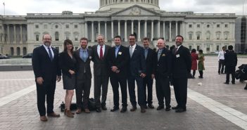 A group of people posing in front of the capitol building.