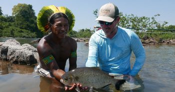 A man holding a fish in a river.