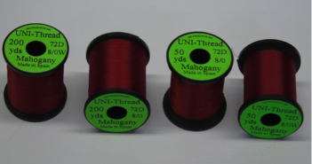 Four spools of red thread with green spools.