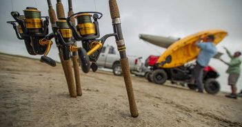 Fishing rods in the sand next to a boat.