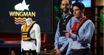 Two men standing next to a wingman vest.