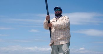 A man standing on a beach holding a surfboard.