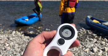 A person holding a remote control in front of a river.