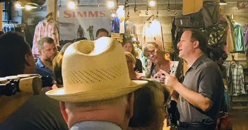 A man in a hat is talking to a group of people in a store.