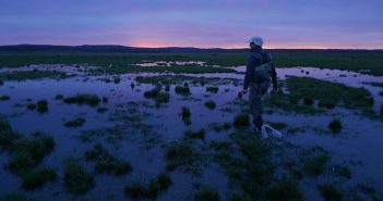 A man standing in a flooded field at dusk.