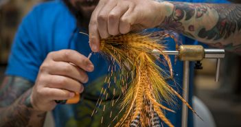 A man is making a fly out of feathers.