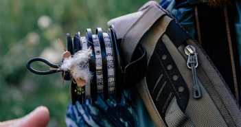 A man is holding a fly tying device in his hand.