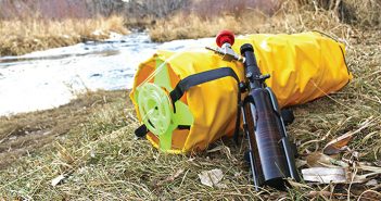 A yellow bag with a gun on it next to a river.