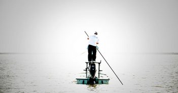 A man standing on top of a boat in the water.