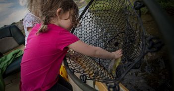 A little girl is fishing in a net on a boat.