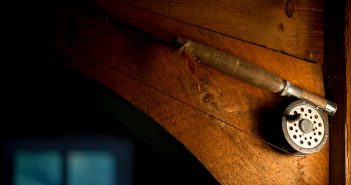 A fishing rod hanging on the side of a wooden door.