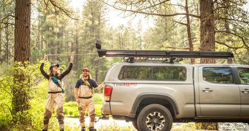 Two people standing on top of a truck.