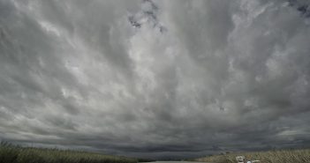 A boat traveling under a cloudy sky.