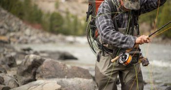 A man is fishing in a river with a fly rod.