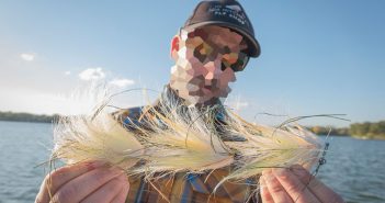 A man holding up some fly flies on a lake.