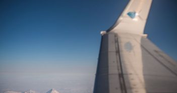 The wing of an airplane with mountains in the background.