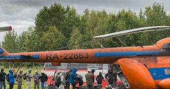 A group of people standing around a helicopter.