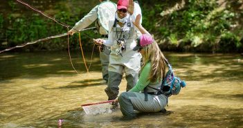 A group of people fishing in a river.