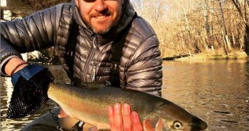 A man holding a trout in the water.