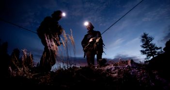 Two men standing on a hill at night.