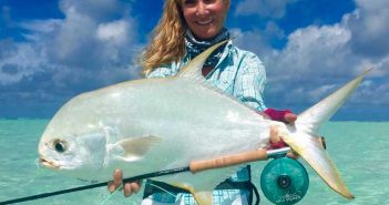 A woman holding up a white fish in the ocean.