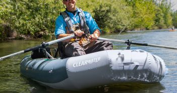 A man is sitting in an inflatable raft on a river.