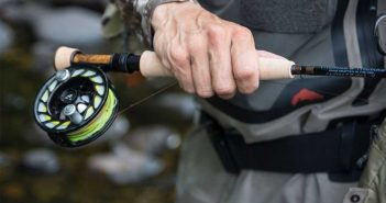 A man holding a fly fishing rod and reel.