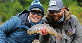 A man and woman holding up a brown trout.