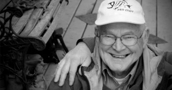 A black and white photo of an older man with a hat.