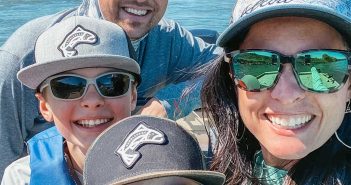 A family on a boat with hats and sunglasses.