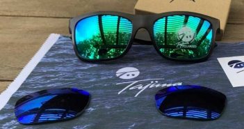 A pair of sunglasses with blue mirrored lenses on a table.