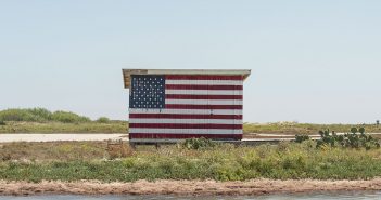 An american flag is painted on a building next to a body of water.