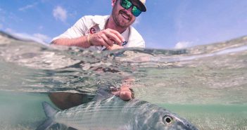 A man holding a fish in shallow water.