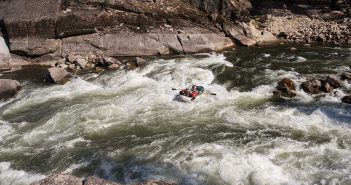 A person is rafting down a rapid in a river.