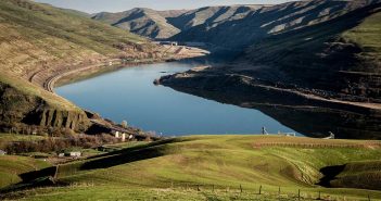 A lake in the middle of a green valley.