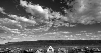 A black and white photo of a group of boats in the desert.