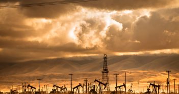 Oil rigs in the desert under a cloudy sky.