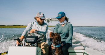 A man and woman on a boat with their dog.