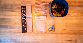 A wooden table with scissors and a bag of granola.