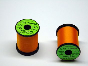 Two orange spools of thread on a white surface.