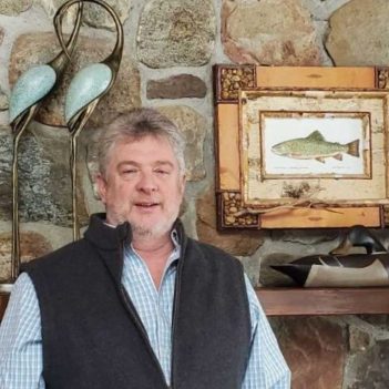 A man standing in front of a stone fireplace.