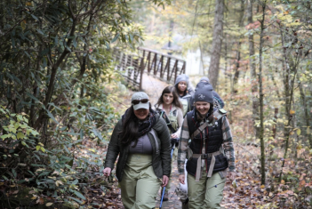 A group of people walking down a trail in the woods.