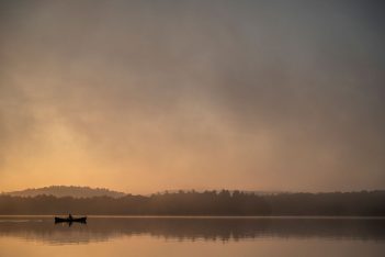 A canoe on a lake at sunrise.