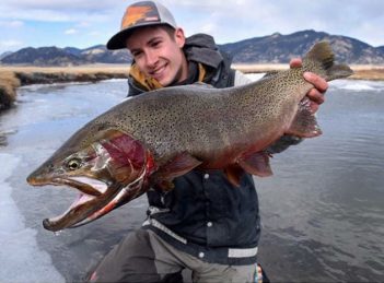 A man holding up a large rainbow trout.