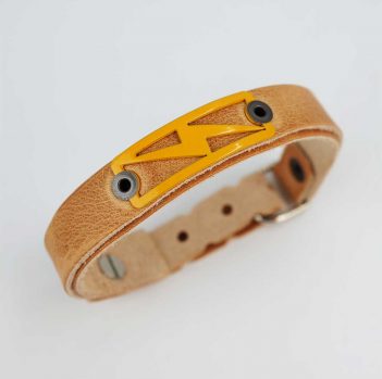 A tan leather bracelet with a yellow logo on it.