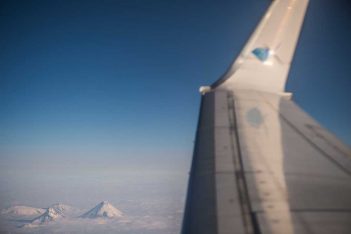 The wing of an airplane with mountains in the background.