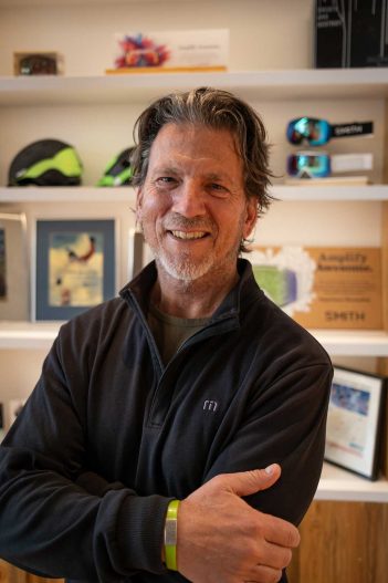 A man standing in front of a shelf full of ski gear.